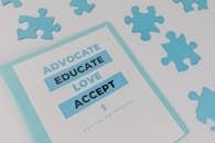 Binder with advocacy message amidst puzzle pieces for autism awareness.